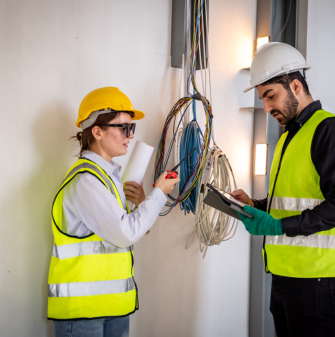 Électriciens analysant câbles électriques au mur.