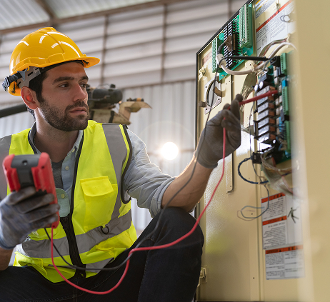 Électricien vérifiant des circuits électriques industriels.